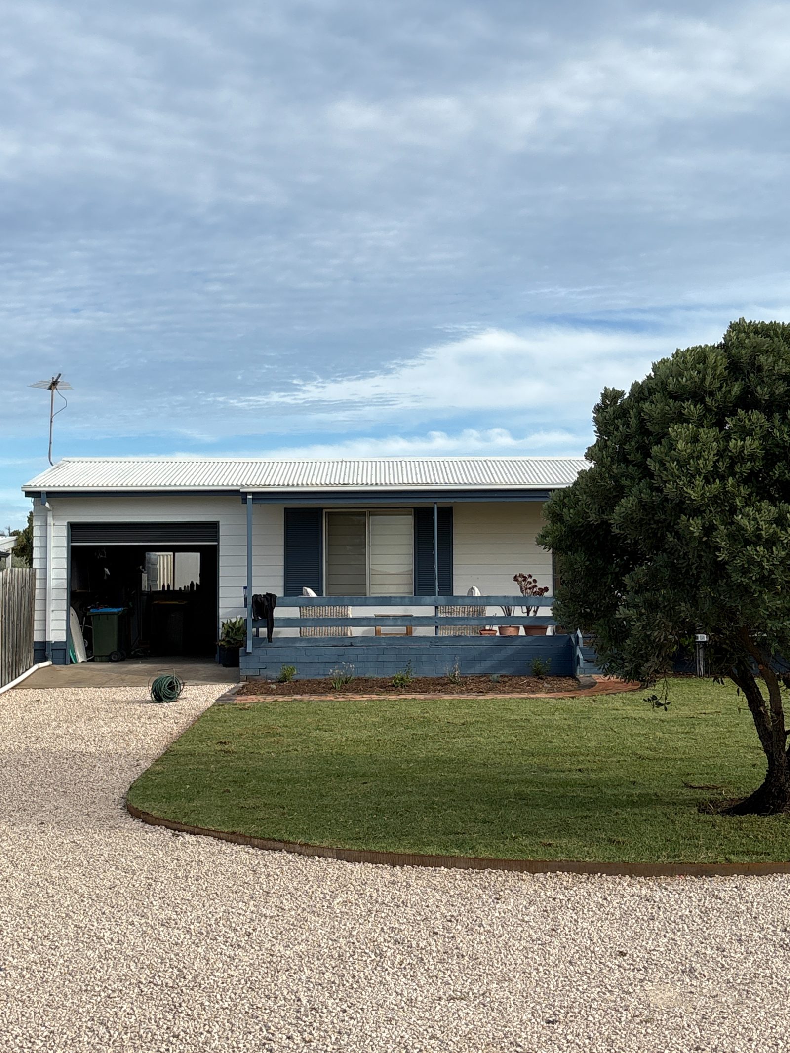 Cottage front garden with a curved lawn, steel edging and gravel driveway